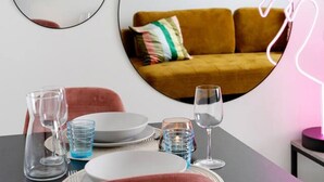 A dining area with a table set for two, a sofa, and a wall with three circular mirrors. - Funky City Apartment By Lapland Host (Rovaniemi)