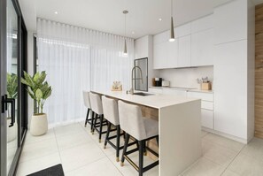 A modern kitchen with a central island, bar stools, and pendant lighting. - Luxury 2BR Condo w/ Rooftop Jacuzzi & Water Views (Laval)