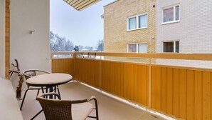 Ein Balkon mit Holzwertung, einem Tisch und zwei Stühlen.