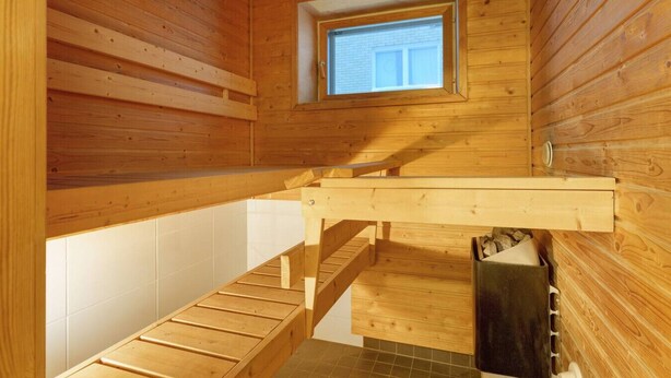 Ein Holzinnenraum mit Fenster, einer Holztreppe und einer gefliesten Wand.