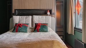 A bed with two pillows, a headboard, and a window with curtains.