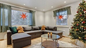 A modern living room with a sectional sofa, a glass coffee table, and a Christmas tree.