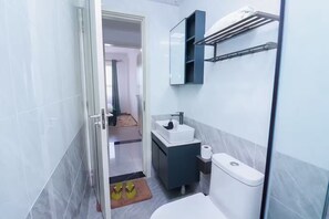A modern bathroom with a toilet, sink, and shower area. - Skyline Splendor with City views, Mini Golf & Spa (Nairobi)