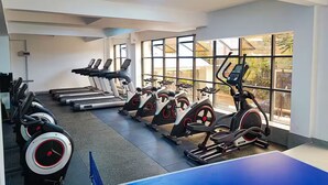 Ein Fitnessraum mit Laufbändern, Crosstrainern und einem Bereich mit blauen Matten.