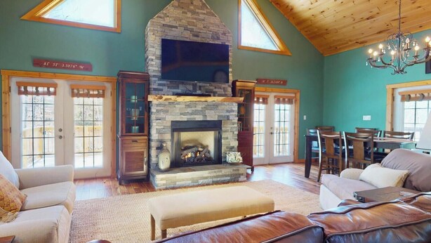 Un salón espacioso con chimenea de piedra, muebles de cuero y ventanas amplias.