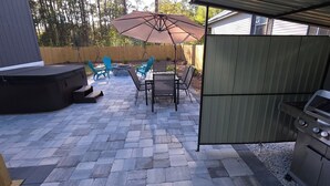 Een terras met een barbecue, buitenmeubilair en een vuurkuil.