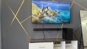 Seinälle asennettu litteänäyttöinen televisio, jossa näkyy merimaisema, sen alla kaiutin ja alla valkoinen mediakeskus, jossa on yksi laatikko.