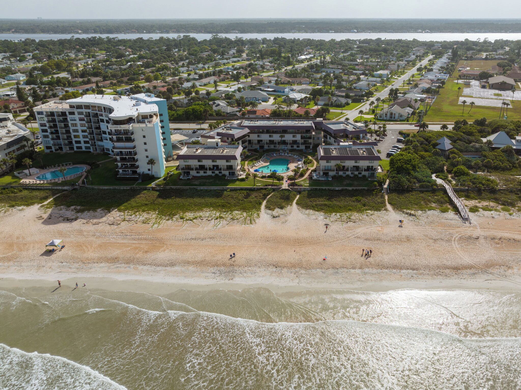 A coastal hotel with multiple buildings, a beach, and a view of the ocean.