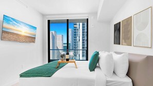 Ein modernes Schlafzimmer mit großem Fenster, einem Bett, einem grünen Teppich und Bildern an den Wänden.