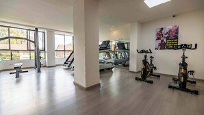 Un gimnasio con máquinas de cardio, equipo de pesas y amplias ventanas.