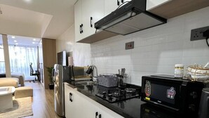 Una cocina moderna con gabinetes blancos, encimera negra y electrodomésticos de acero inoxidable.