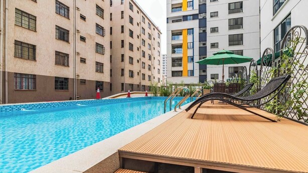 Una piscina con cubierta de madera, rodeada de edificios de varios pisos con balcones.