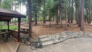 A wooden deck with outdoor furniture, a stone patio, and a forested area with a gazebo. - Cozy 2-bedroom cabin in Pollock Pines, Apple Hill/Gold Country (Pollock Pines)