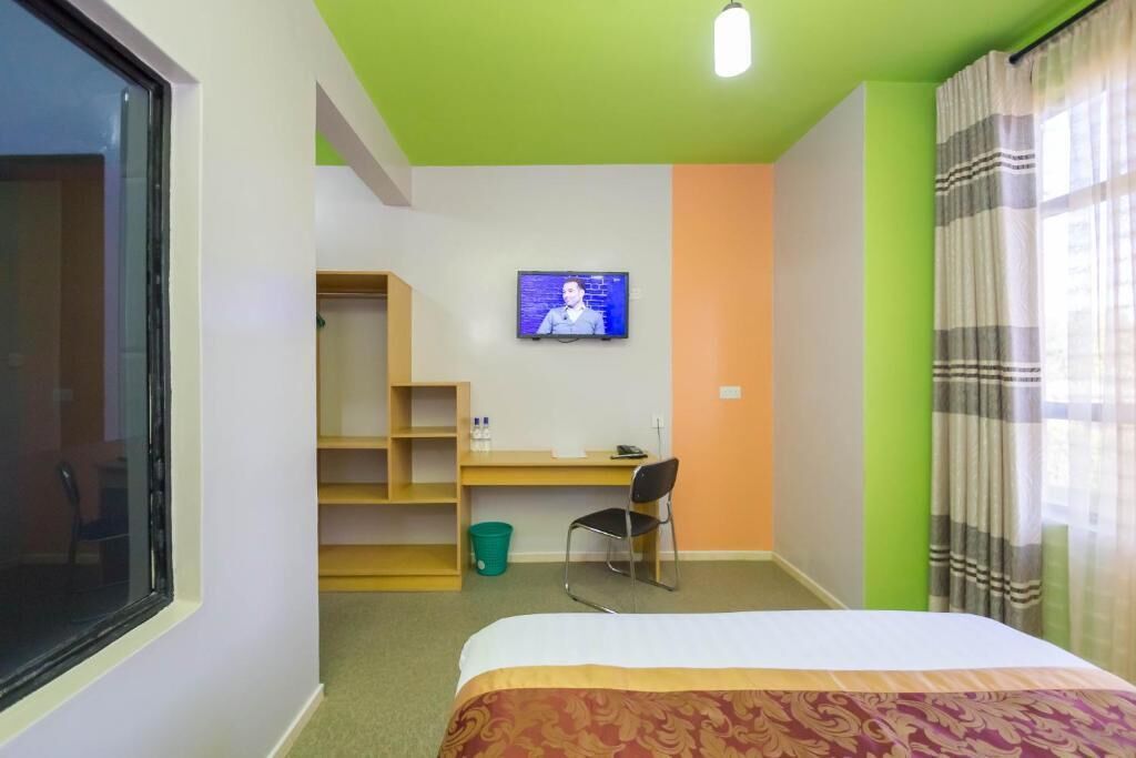 Une chambre d’hôtel équipée d’un lit, d’un bureau, d’une chaise, d’une télévision et d’une fenêtre.