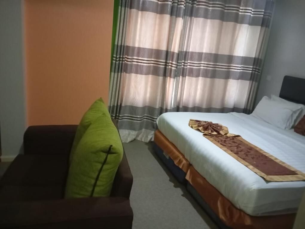 Una habitación de hotel con una cama, un sofá y cortinas.