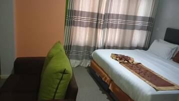 Una habitación de hotel con una cama, un sofá y cortinas.