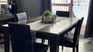 Een eetruimte met een tafel, stoelen, een koffiezetapparaat en uitzicht op een besneeuwd landschap.