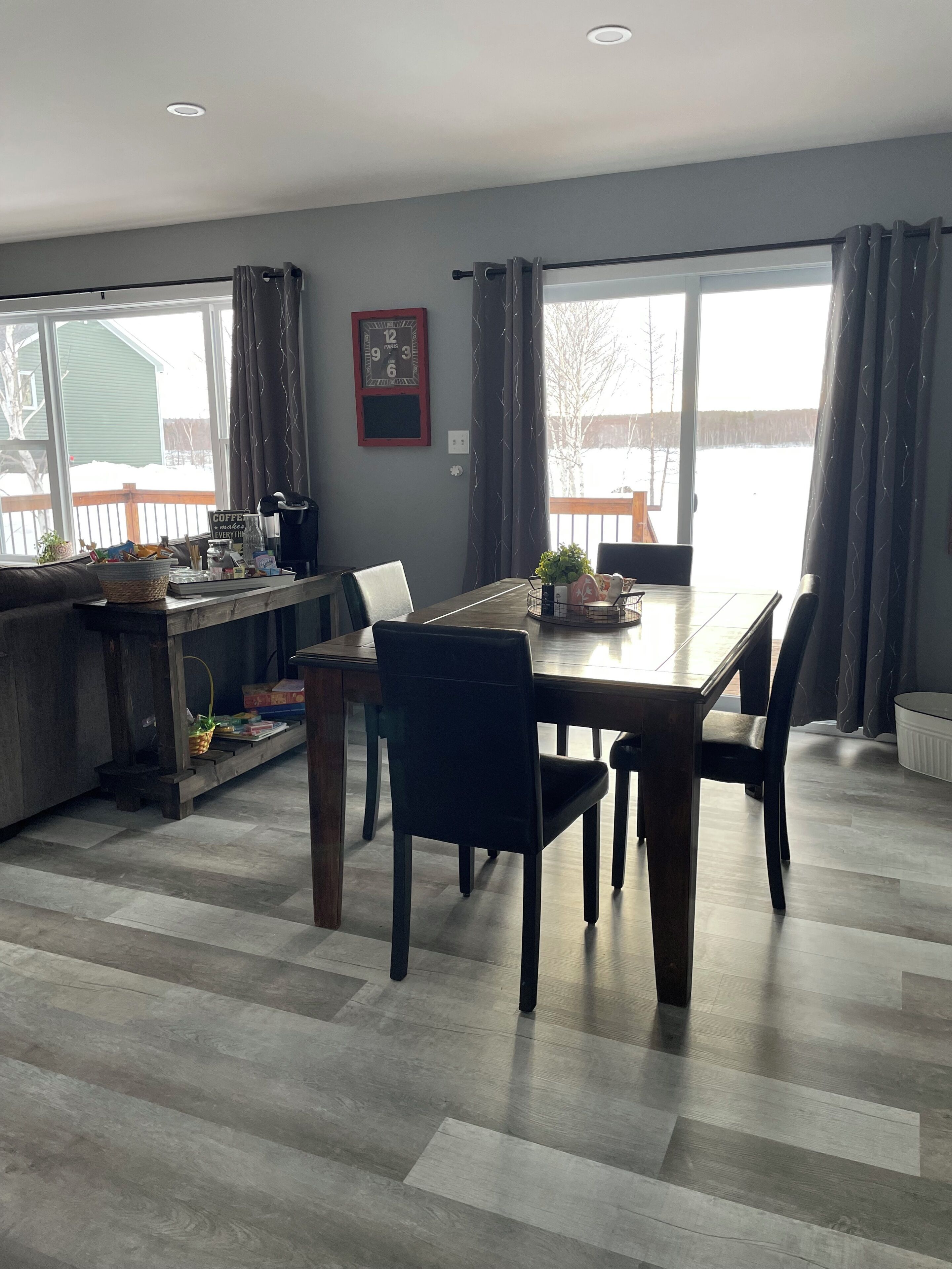 A dining area with a table, chairs, a kitchen counter, and a large window with curtains.