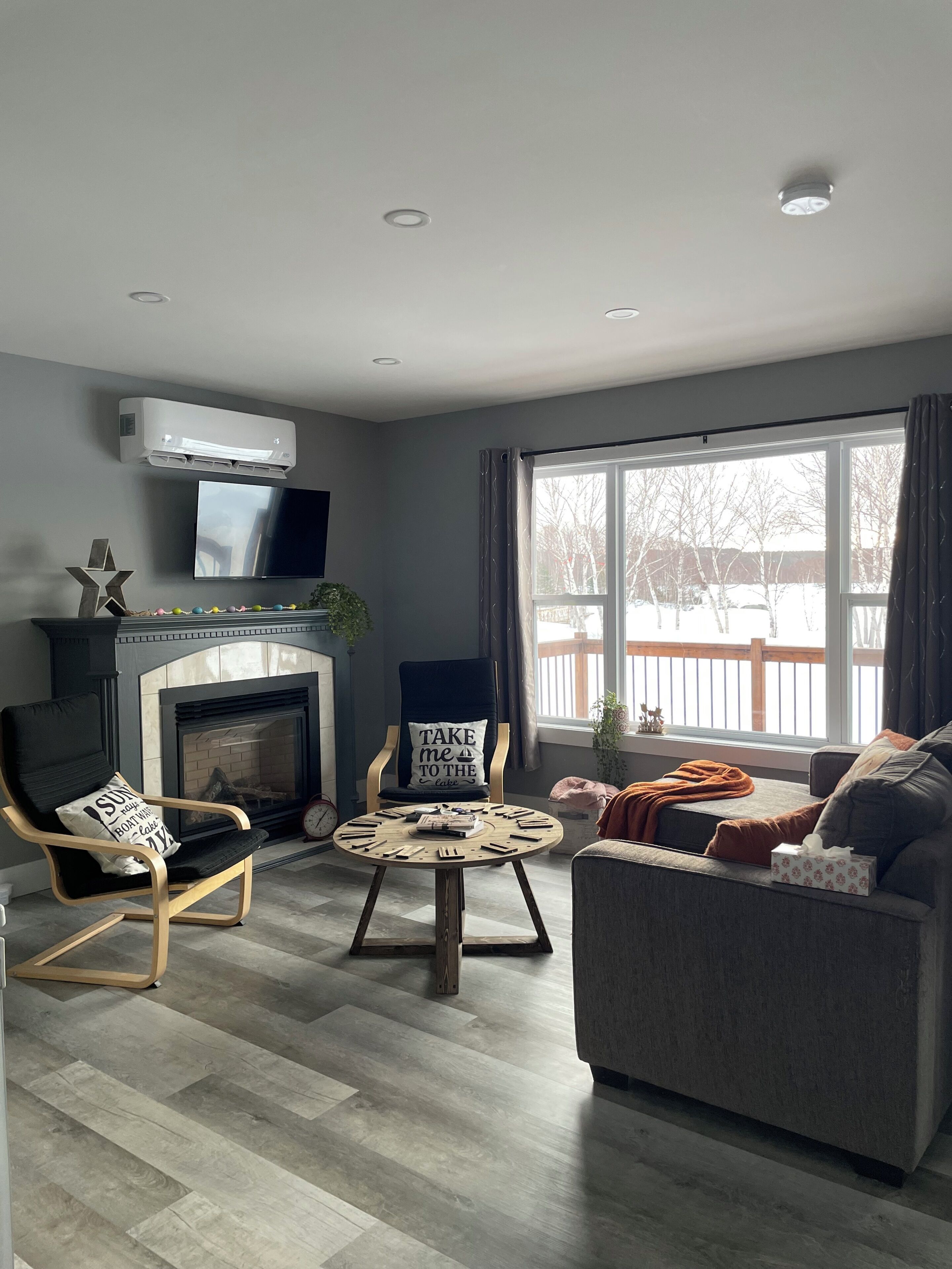 A modern living room with a fireplace, a television, and a large window.