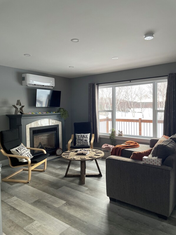 A modern living room with a fireplace, a television, and a large window.