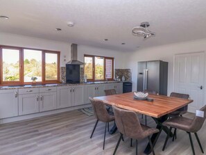 A modern kitchen with a dining area, featuring a large wooden table and grey cabinets. - Star Carr Lakes (Driffield)
