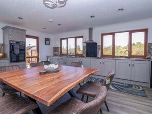 Cozinha moderna com mesa de jantar de madeira, armários cinzas e vista para o exterior.