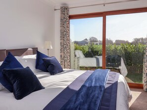 Quarto com uma cama grande, vista para um jardim e porta de vidro deslizante.