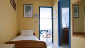 Une chambre avec un lit, un bureau et une chaise. Elle possède un balcon avec vue.