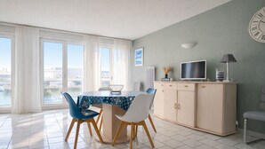 Un espace repas moderne comprenant une table, des chaises, un meuble et un téléviseur.