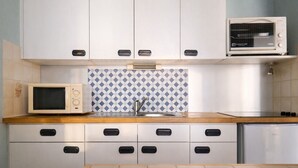 Une cuisine avec des armoires blanches, un four à micro-ondes, un grille-pain et un évier.
