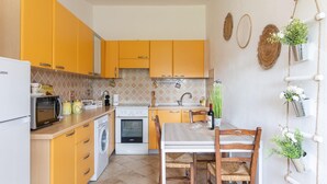 Cozinha compacta com armários amarelos, micro-ondas, fogão e pia.