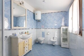 Un bagno con lavandino, WC, bidet e specchio.
