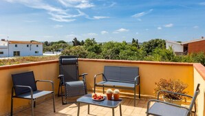 Terraço no telhado com duas cadeiras, uma mesa e um vaso de planta.