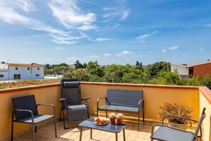 Eine Dachterrasse mit zwei Stühlen, einem Tisch und einer Topfpflanze.