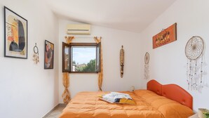 Quarto com cama, janela, ar condicionado e decorações nas paredes.