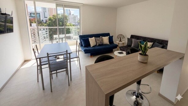 A modern living space with a dining area, a sofa, and a large window offering a city view. - Modern & Exclusive | Stunning View (Manizales)