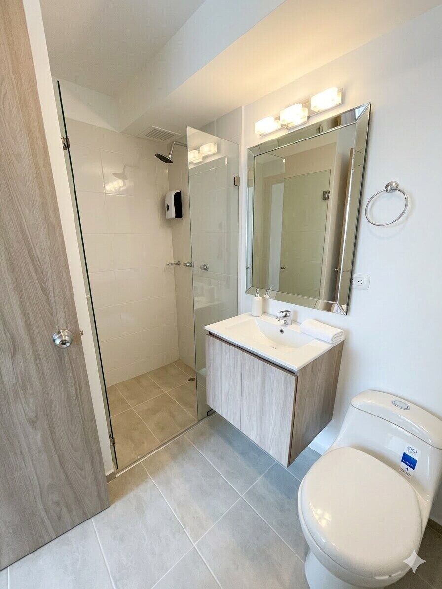 A modern bathroom with a glass shower enclosure, a vanity with a mirror, and a toilet.