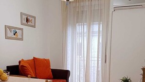 A living room with a dining area, a sofa, a table, chairs, a hanging light fixture, and a window with curtains. - Chanzerhouse (Fondi)
