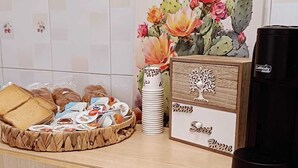 A kitchen counter with a coffee maker, a basket of bread, a tray of pastries, and a decorative cactus plant. - Chanzerhouse (Fondi)