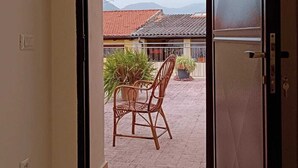 An open door leading to a patio with a chair and potted plants. - Chanzerhouse (Fondi)
