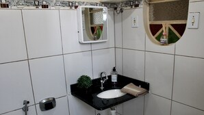 Casa de banho com lavatório preto, espelho e porta-toalhas.