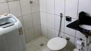 Um banheiro pequeno e compacto, com vaso sanitário branco, pia e máquina de lavar roupa.
