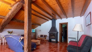 Una habitación acogedora con techo alto, chimenea, sofá, sillón y lámpara.