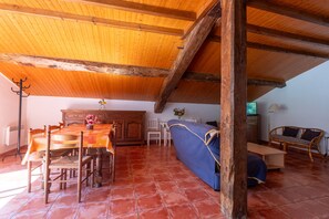 Un intérieur rustique avec un plafond en bois, une table à manger avec des chaises, un canapé et un téléviseur.