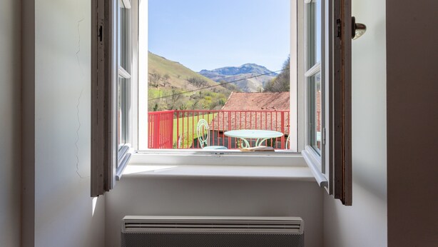 A window with a view of a red fence, a table, and a chair outside. - Charming Little Yaitua with Mountain View, Private Terrace and Wi-Fi (Estérençuby)