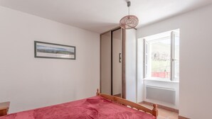A bedroom with a bed, a window, a door, and a hanging light fixture. - Charming Little Yaitua with Mountain View, Private Terrace and Wi-Fi (Estérençuby)