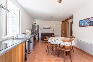 Cozinha com pia, fogão e mesa de jantar com cadeiras.