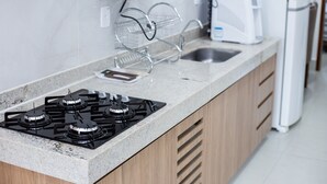 Una cucina con piano cottura a gas, forno a microonde, macchina del caffè e frigorifero.