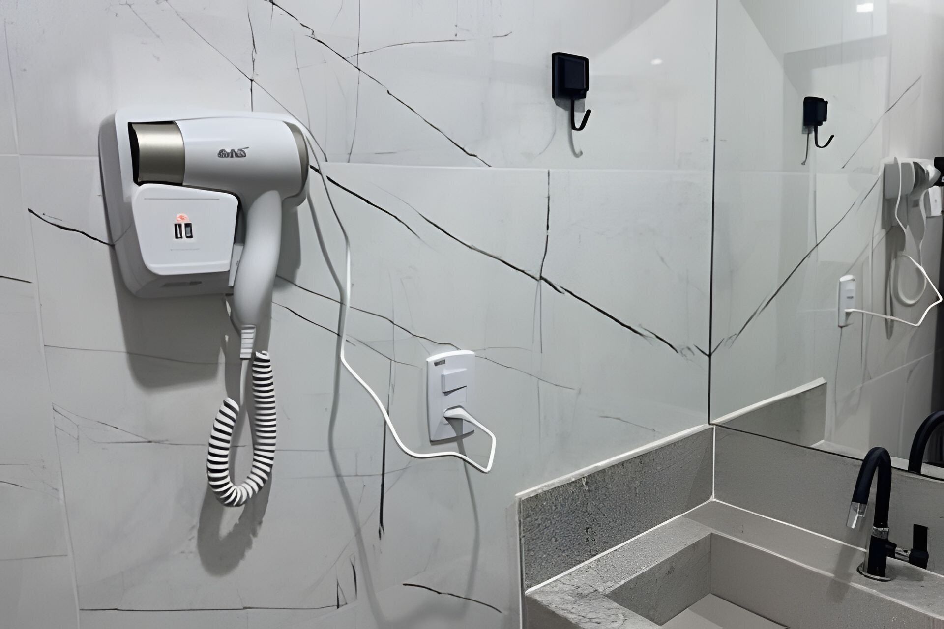 Une salle de bain équipée d’un sèche-cheveux, d’un téléphone et d’un miroir.
