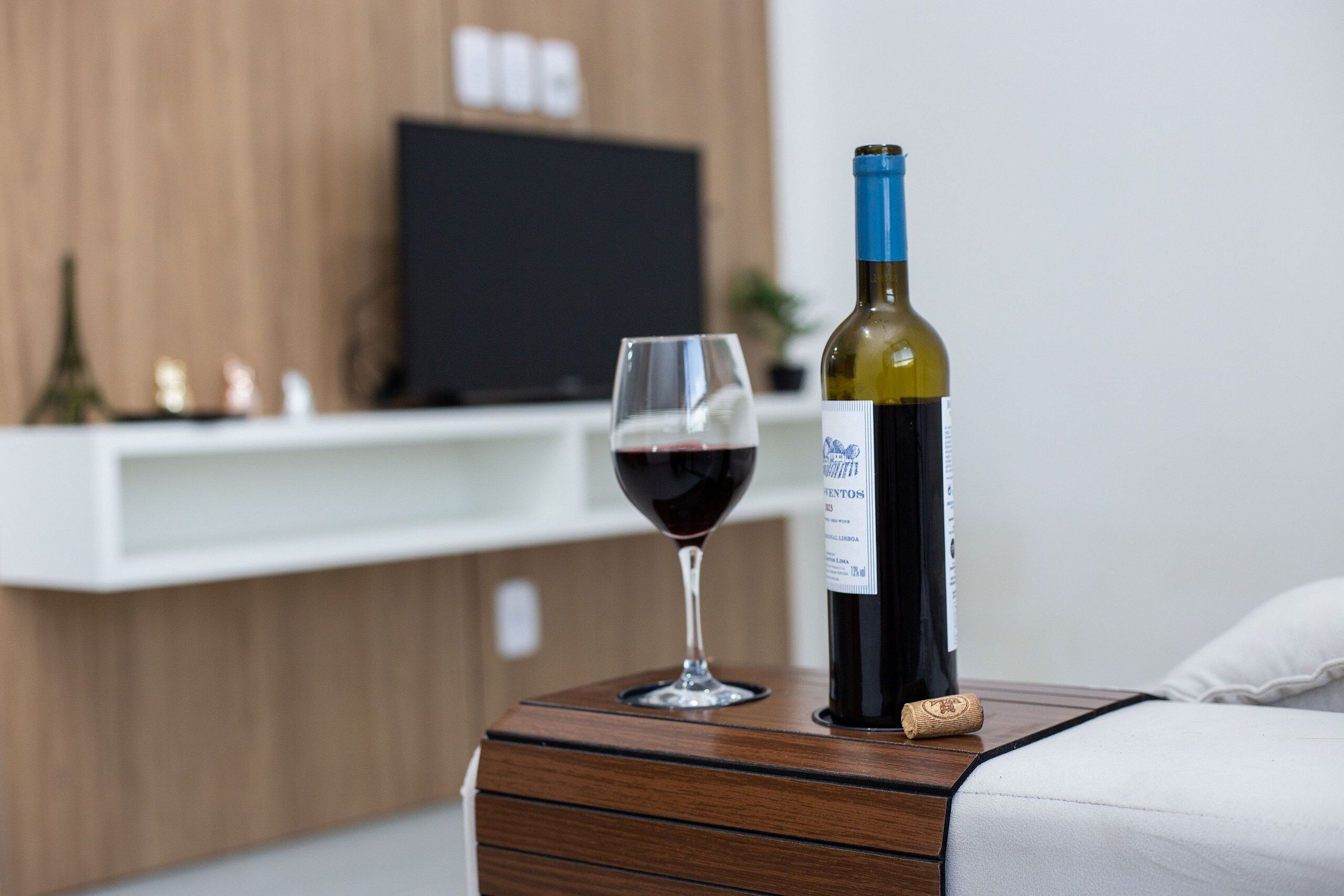 Eine Weinflasche und ein Glas auf einem Holztisch im Hotelzimmer.